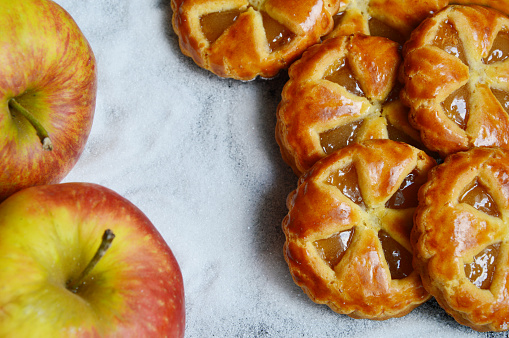 Mini apple pies with fresh apples and sugar background