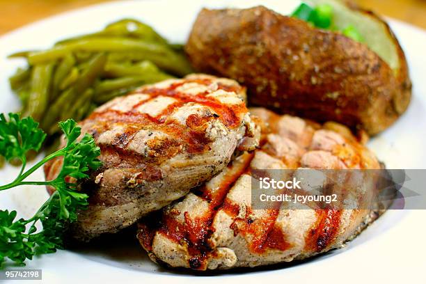 Chuleta De Cerdo Con Deliciosa Comida Con Papas Al Horno Foto de stock y más banco de imágenes de Al horno