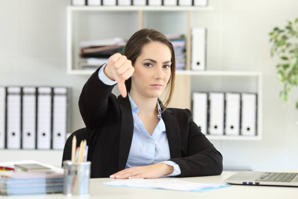 Businesswoman denying with thumbs down Front view portrait of an angry businesswoman denying with thumbs down at office thumb down stock pictures, royalty-free photos & images