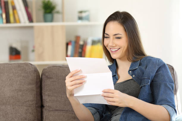 istock Happy woman reading a letter on a couch at home 957422874