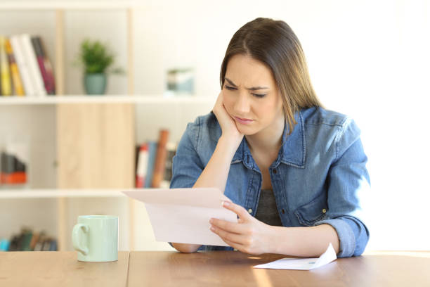 istock Worried female reading a letter on a table at home 957422968