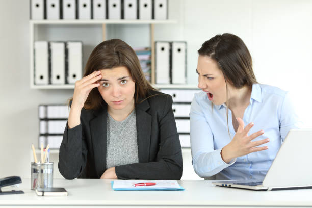 Boss scolding an emlployee looking at camera Boss scolding an emlployee who is looking at camera at office melancholy computer support specialist stock pictures, royalty-free photos & images