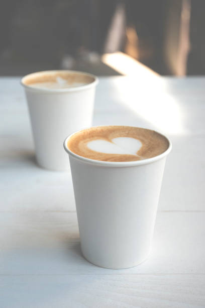 dwie białe papierowe filiżanki kawy na drewnianym stole. - latté cafe macchiato glass cappuccino zdjęcia i obrazy z banku zdjęć