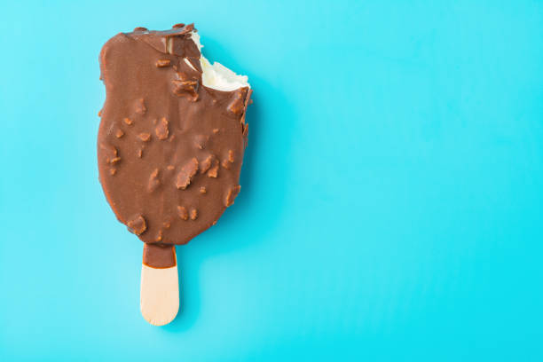 istock top view chocolate outer ice cream with a bite on a blue background close up 957434410