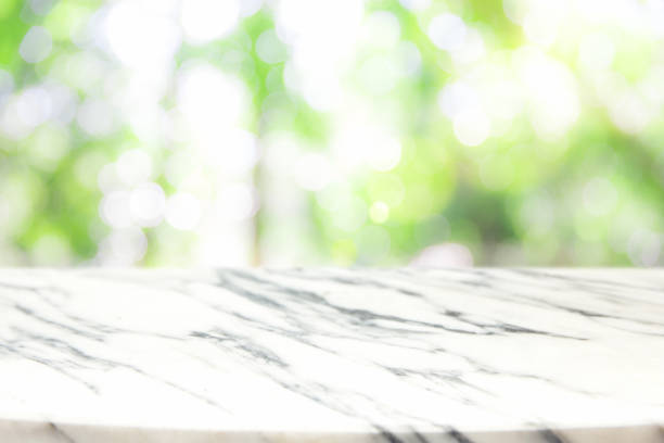istock Blank marble table top with sun and blur green tree. 957444734