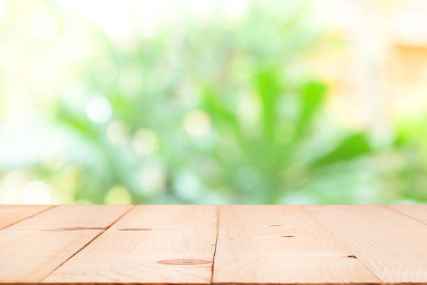 istock Blank wood table top with sun and blur green tree. 957447766