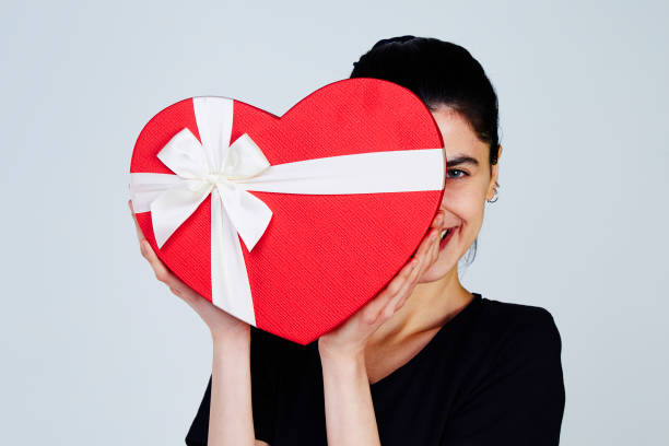 istock Young Woman holding heart shape gift box 957447878