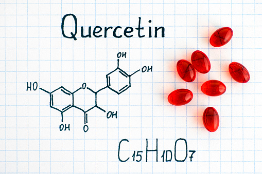 Chemical formula of Quercetin with red pills. Close-up.