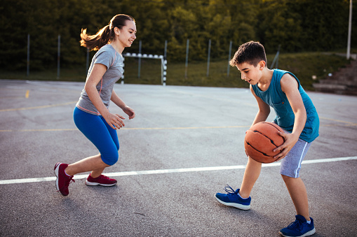 Photo of boy with his friend playing basketball outdoors