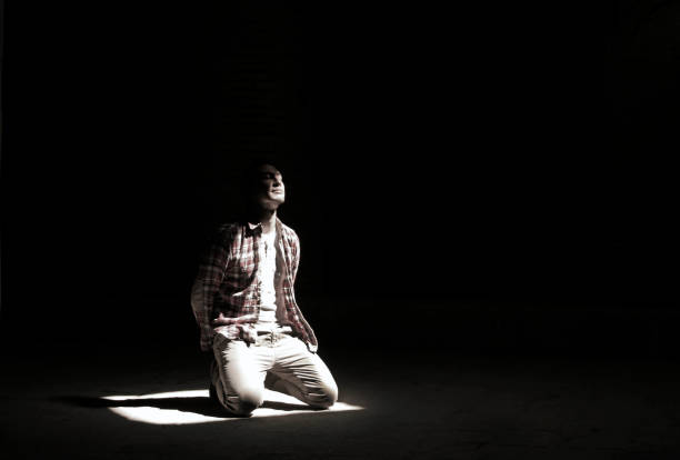 istock Man kneeling in a a bright beam of light 957469260
