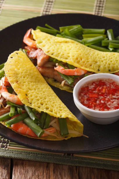 banh xeo crepes stuffed with pork, shrimp, onions, bean sprouts and spicy sauce closeup. vertical - nuoc imagens e fotografias de stock