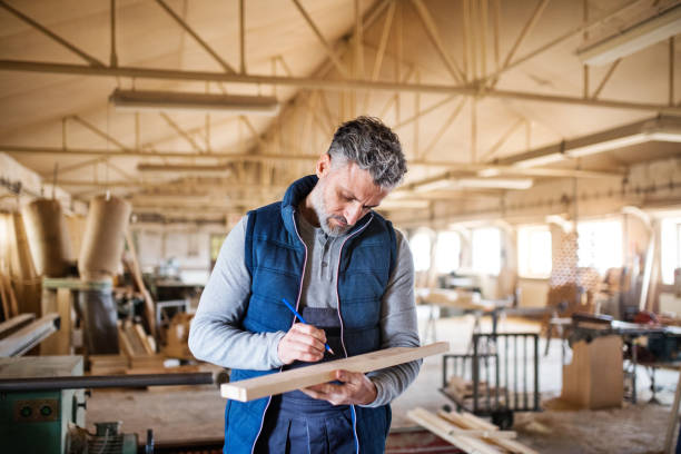 istock A man worker in the carpentry workshop, working with wood. 957473336