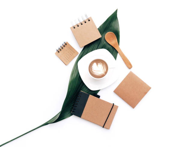 istock Flat lay Modern blogger concept. Workspace with eco Kraft items coffee and green leaf on white background. 957479942