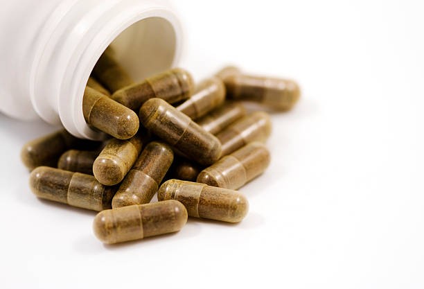 istock Herbal capsules spilling from bottle isolated on white 95748656