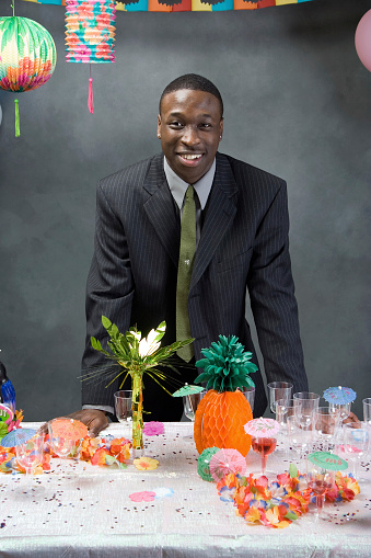 An african american guy standing in front of a table at prom