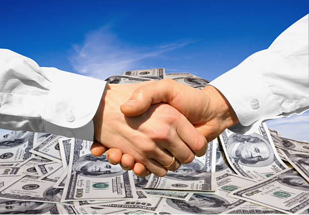 istock Two hands shaking with money in the background 95750579