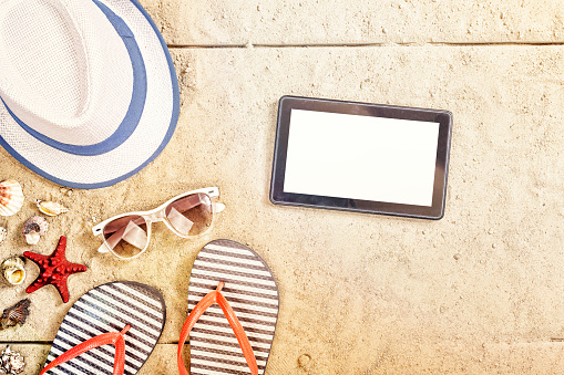 Summer vacation composition. Sandals, sunglasses, hat, tablet and smartphone. cope space top view