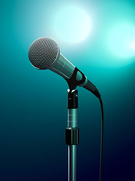 Up close photo of a microphone mounted on a stand Microphone on stage with turquoise stage lights. audition photos stock pictures, royalty-free photos & images