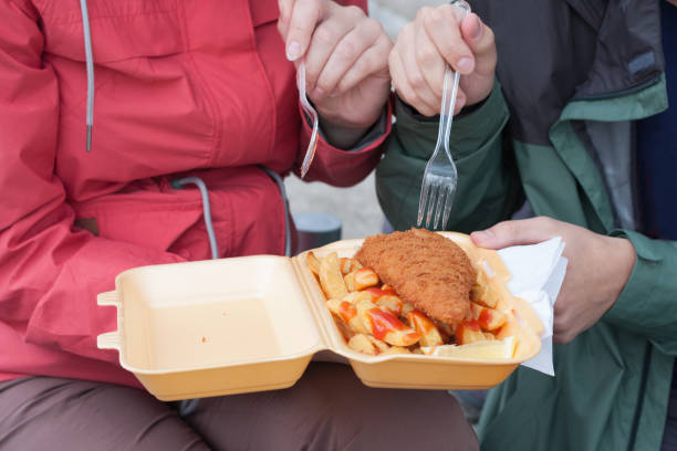 pareja joven come tradicional londres comida pescado y patatas fritas - plastic knife fotografías e imágenes de stock