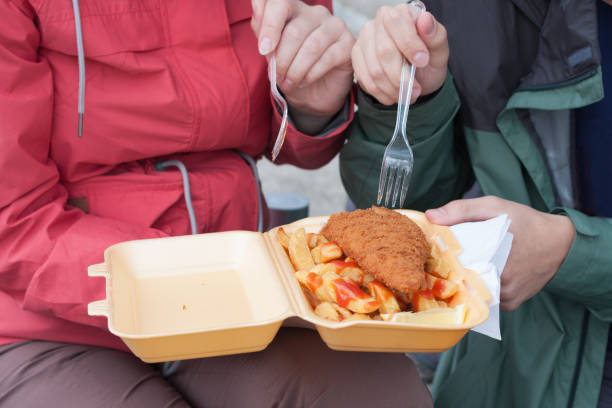 молодая пара ест традиционную лондонскую рыбу и чипсы - plastic knife стоковые фото и изображения