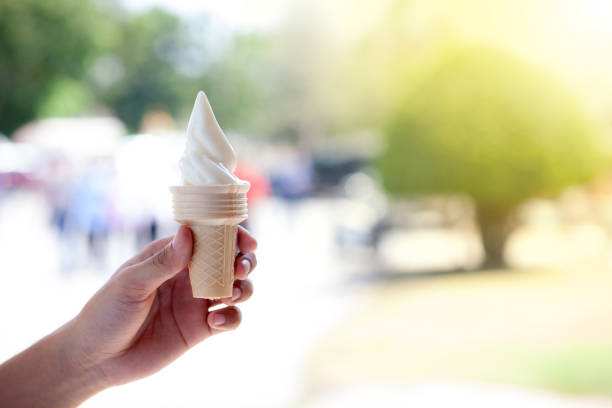 istock Hands holding ice cream waffle cone in public park on summer 957516910