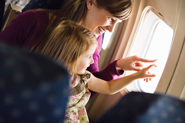 woman and girl pointing out airplane window - airplane window indoors looking through window - fotografias e filmes do acervo