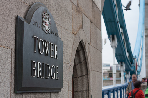 Street sign Tower Bridge on wall, on background walking tourist on September 7, 2017 in London