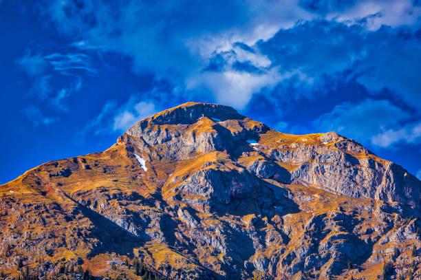 Industrial steel structure of a cable car tower in front of a massive mountain face.