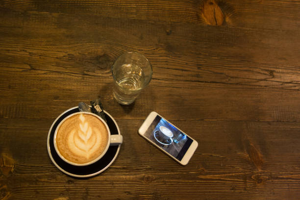istock Cup of coffee with phone 957535326
