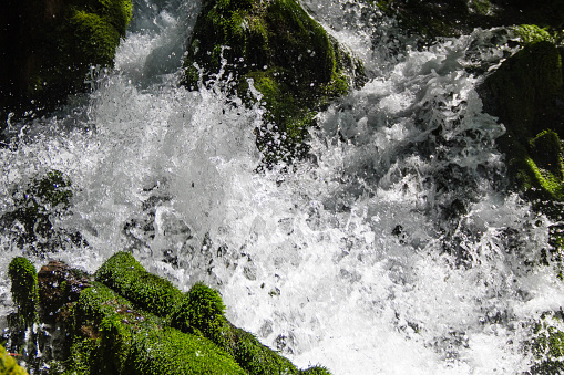 Close up photo of a fresh clean waterfall surrounded by green moss covered rocks.