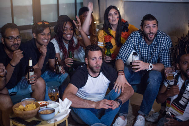 istock Soccer fans cheering at home 957567370