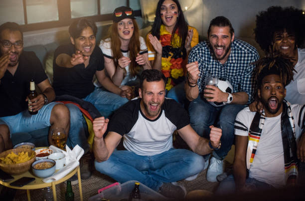 istock Soccer fans cheering at home 957570100