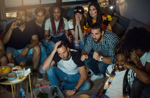istock Soccer fans cheering at home 957570682