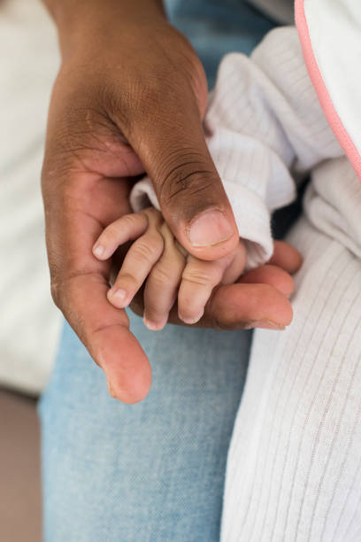 istock Baby girl hand resting on fathers hand 957570736