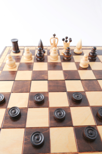 Close-up of king and queen chess pieces on chessboard against black background.