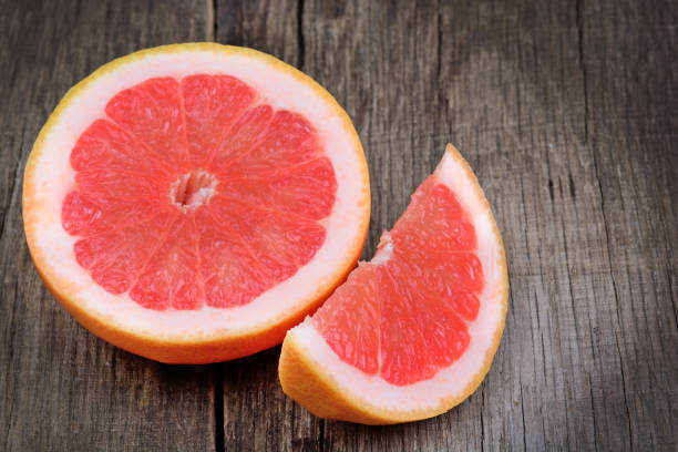 istock Half and piece of red grapefruit on wood table 957580800