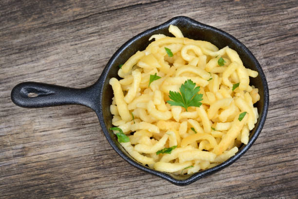 Spaetzle with butter and parsley in a iron pan on wood table stock photo