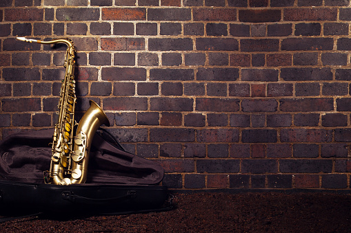 Saxophone leaning against a red brick wall