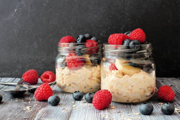 istock Overnight oats with berries in jars on a dark background 957588622