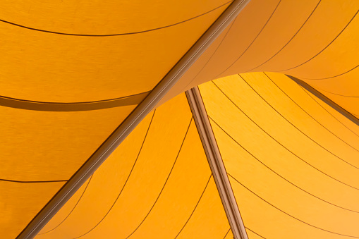 Geometric shaped yellow sails used to provide shade to the forecourt of entranceway
