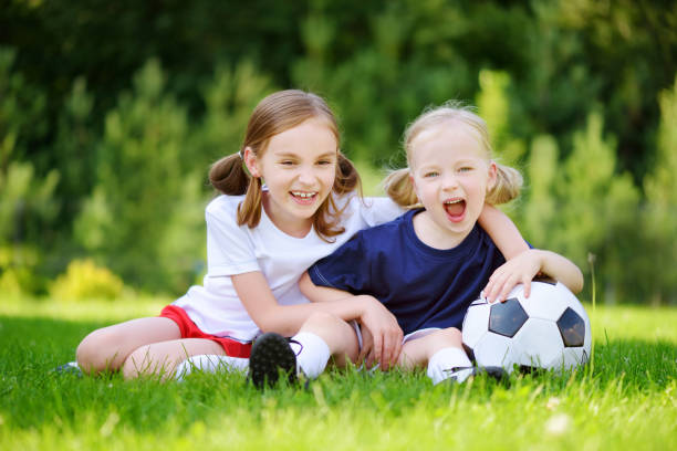 istock Two cute little sisters having fun playing a soccer game 957598560