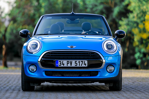 İzmir, Turkey. August 6, 2017. Front side view of a mint condition blue Mini Cooper with black leather interior parked in Gaziemir district of İzmir. In the view there are the headlight, Black aluminium wheels, a rearview mirror, a turn signal