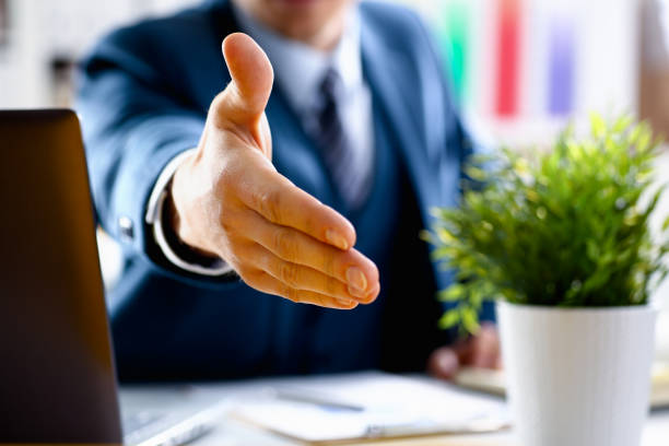 istock Man in suit and tie give hand as hello in office 957604968