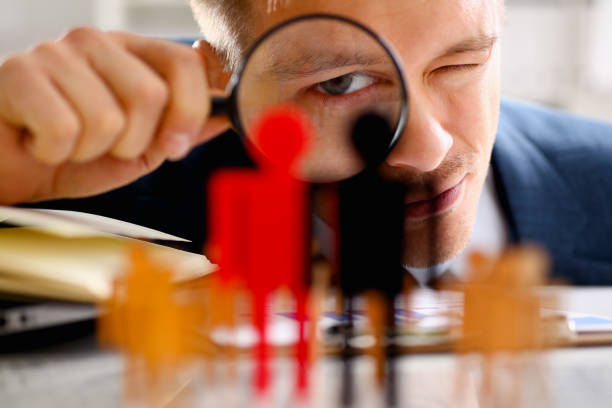 istock Man in suit look thru loupe on statuettes closeup 957605016