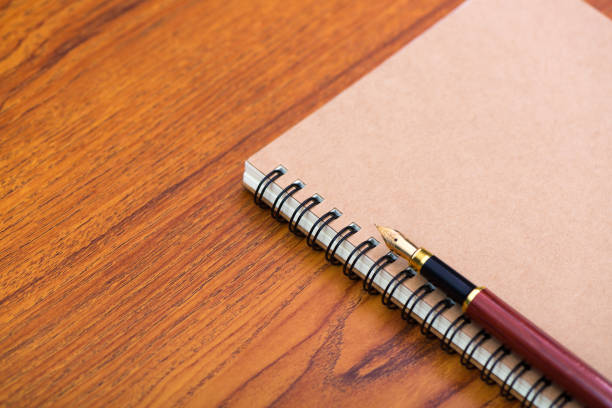 istock Fountain pen or ink pen with notebook paper on wooden working table with copy space, office desk concept. 957605078