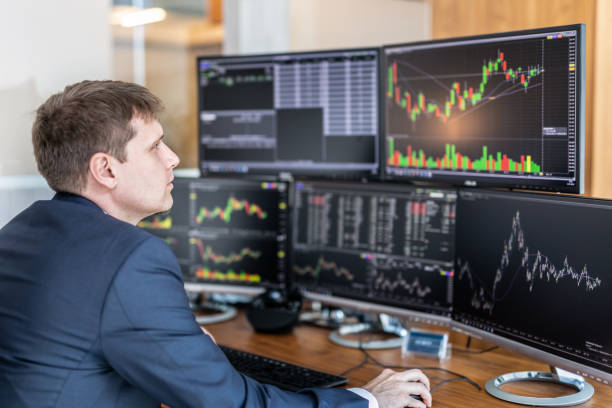 istock Stock trader looking at computer screens in trdading office. 957605170