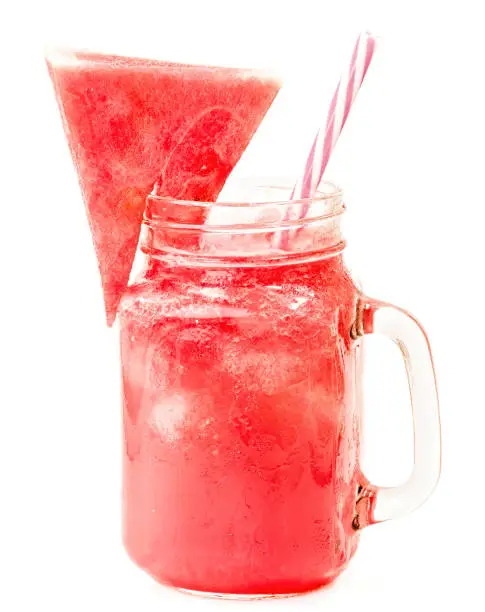 Photo of watermelon smoothie in a mason jar decorated with a slice of watermelon isolated on white background. fruit smoothie with a drinking straw isolated