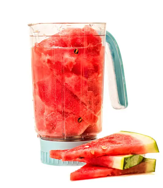 Photo of watermelon and mineral water in a blender. making a smoothie in a blender. blender with watermelon and watermelon pieces isolated on white background