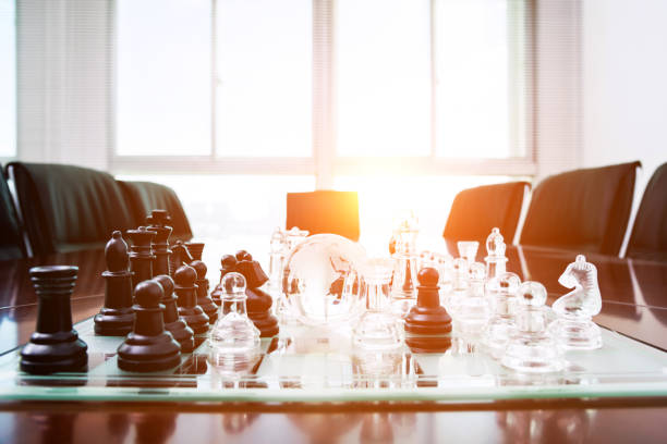 istock Chess pieces and glass earth globe on the conference table 957612556