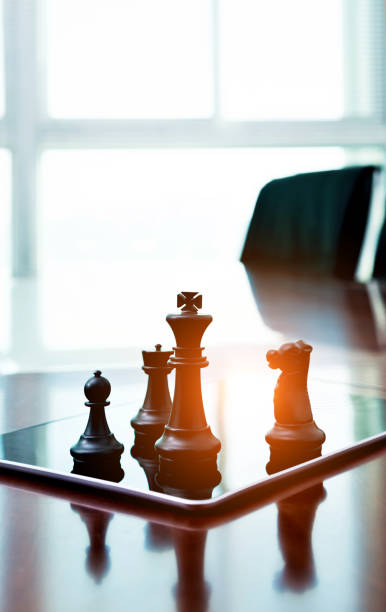 istock Chess pieces standing on the digital tablet 957612630